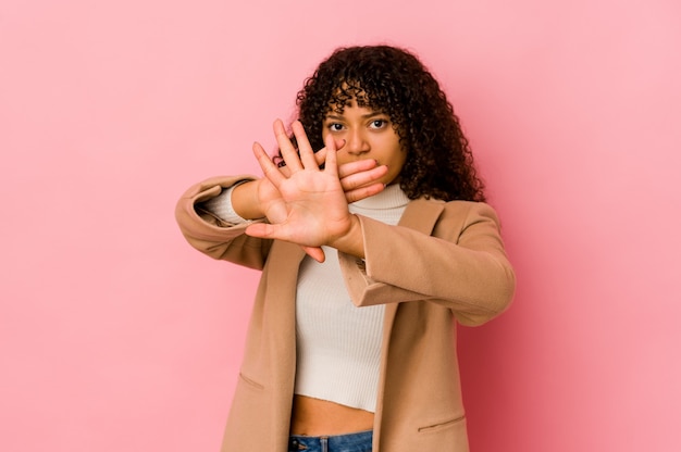 Jonge afrovrouw geïsoleerde status met uitgestrekte hand die stopbord toont, dat u verhindert