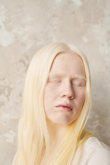 Jonge albinovrouw met een bleke huid en heel blond haar die de ogen gesloten houdt