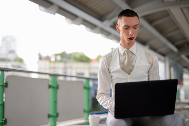 Jonge androgyne homoseksuele LGTB-zakenman die laptop computer met behulp van