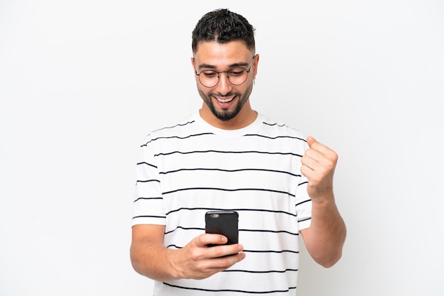Jonge Arabische knappe man geïsoleerd op een witte achtergrond verrast en stuurt een bericht