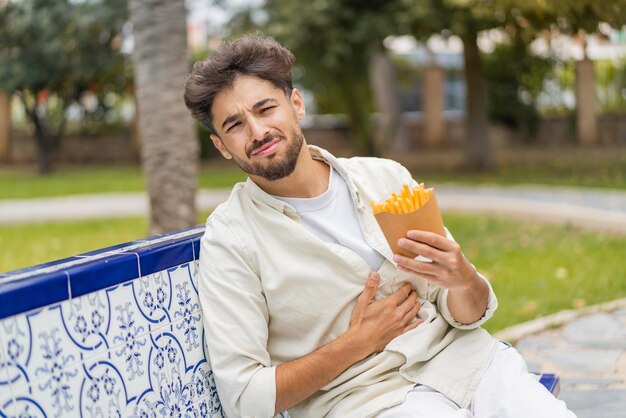 Jonge Arabische knappe man met gebakken chips buitenshuis