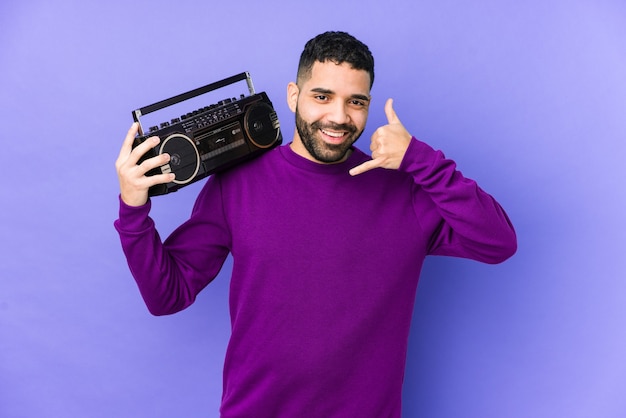 Jonge Arabische man met een radio cassette geïsoleerd Jonge Arabische man luisteren muziek met een mobiele telefoongesprek gebaar met vingers.