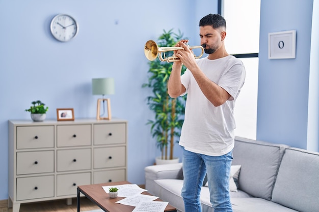 Jonge arabische man muzikant die trompet speelt die thuis staat