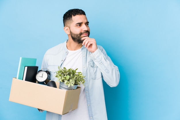 Jonge Arabische man verhuizen naar een nieuw huis geïsoleerd opzij kijken met twijfelachtige en sceptische uitdrukking.