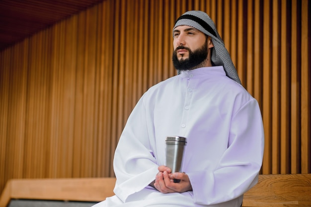 Jonge Arabische man zit op een houten bankje met metaal