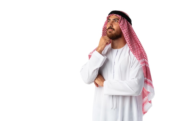 Jonge arabische mens die traditionele kleding draagt die aan iets denkt