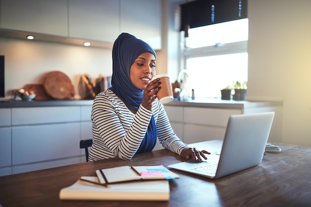 Jonge Arabische ondernemer die koffie drinkt terwijl ze in haar keuken werkt