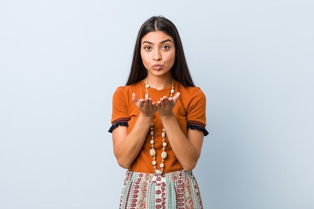 Jonge Arabische vrouw die lippen vouwen en palmen houden om luchtkus te verzenden.