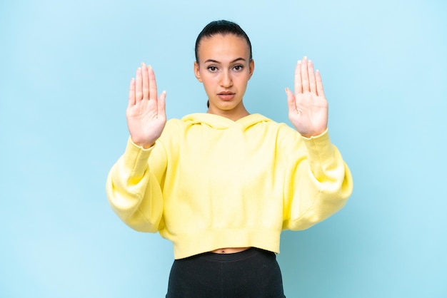 Jonge Arabische vrouw geïsoleerd op blauwe achtergrond maken stop gebaar en teleurgesteld