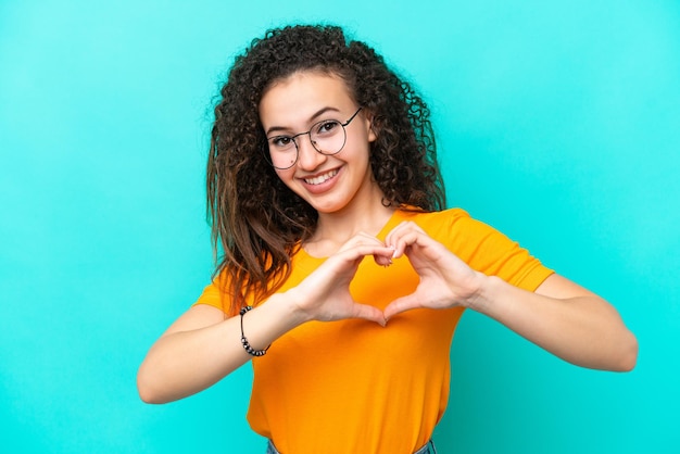 Jonge arabische vrouw geïsoleerd op blauwe achtergrond met bril maken hart met handen