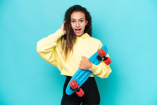 Jonge Arabische vrouw geïsoleerd op blauwe achtergrond met een skate en verrassingsgebaar doen