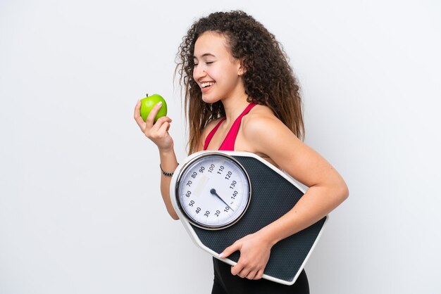 Jonge Arabische vrouw geïsoleerd op een witte achtergrond met weegmachine en met een apple