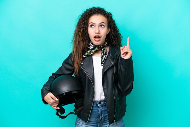 Jonge Arabische vrouw met een motorhelm geïsoleerd op blauwe achtergrond denken een idee met de vinger omhoog