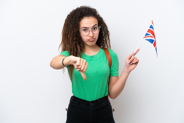 Jonge Arabische vrouw met een vlag van het Verenigd Koninkrijk geïsoleerd op een witte achtergrond met duim omlaag met negatieve uitdrukking