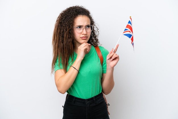 Jonge arabische vrouw met een vlag van het verenigd koninkrijk geïsoleerd op een witte achtergrond met twijfels en denken