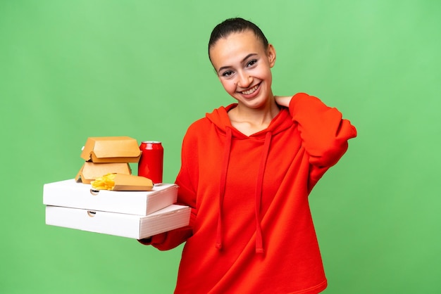 Jonge Arabische vrouw met fastfood over geïsoleerde lachende achtergrond