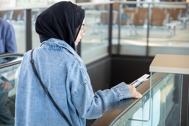 Foto jonge arabische vrouw met haar paspoort op de luchthaven klaar voor een nieuw avontuur met vliegtuig op de achtergrond