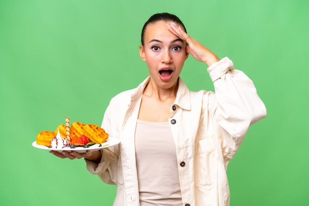 Jonge Arabische vrouw met wafels over geïsoleerde achtergrond met verrassingsuitdrukking