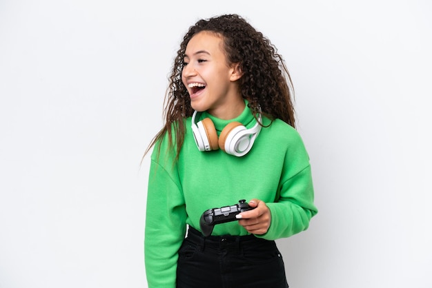 Jonge Arabische vrouw spelen met een video game controller geïsoleerd op een witte achtergrond lachen in laterale positie