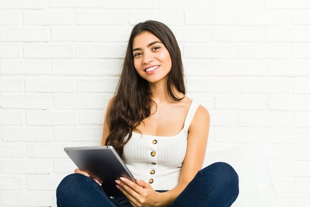 Jonge Arabische vrouw zittend op het bed met behulp van een tablet