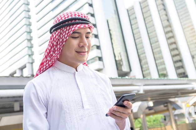 Jonge arabische zakenman met behulp van de mobiele telefoon tijdens het wandelen in de stad.