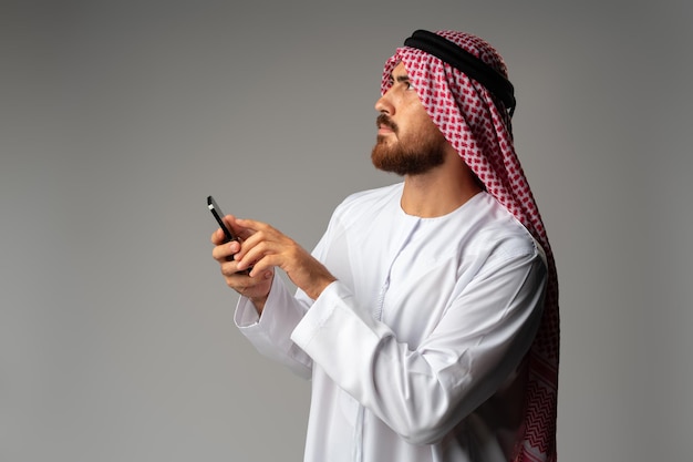 Jonge Arabische zakenman met een smartphone op een grijze achtergrond