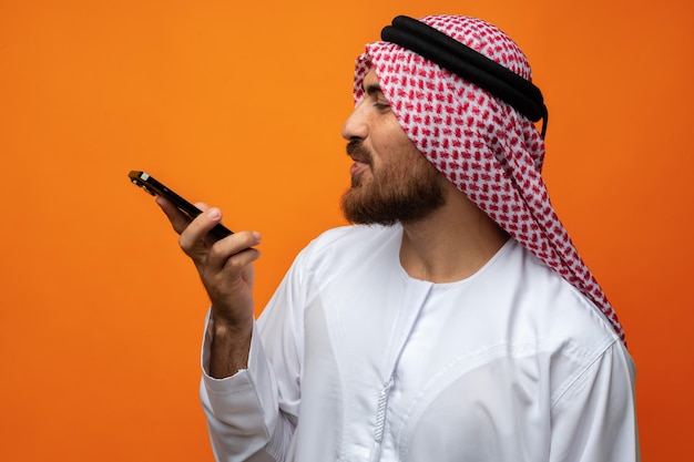 Jonge Arabische zakenman met een smartphone op oranje achtergrond