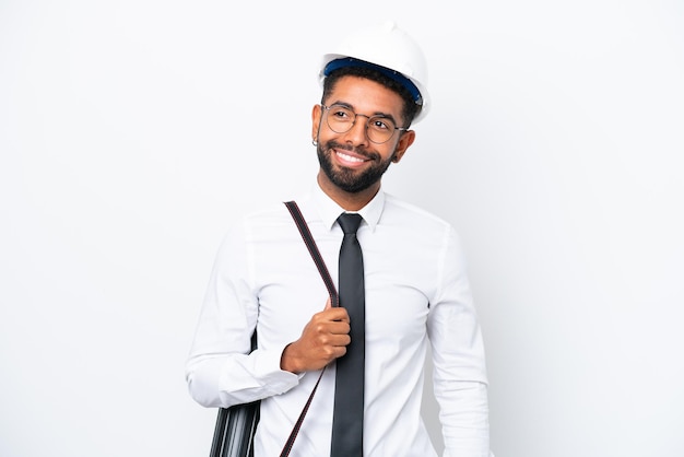 Jonge architect Braziliaanse man met helm en met blauwdrukken geïsoleerd op een witte achtergrond die een idee denkt terwijl hij omhoog kijkt