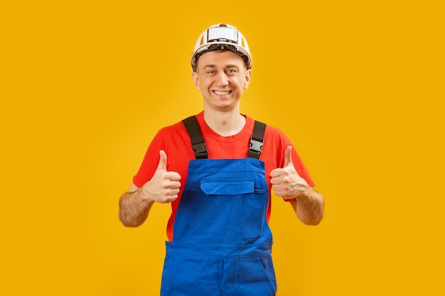 Jonge architect man of ingenieur of werknemer over geïsoleerde gele achtergrond toont duimen omhoog en glimlach kopie ruimte