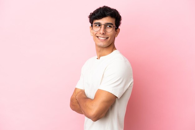 Jonge Argentijnse man geïsoleerd op roze achtergrond met gekruiste armen en happy