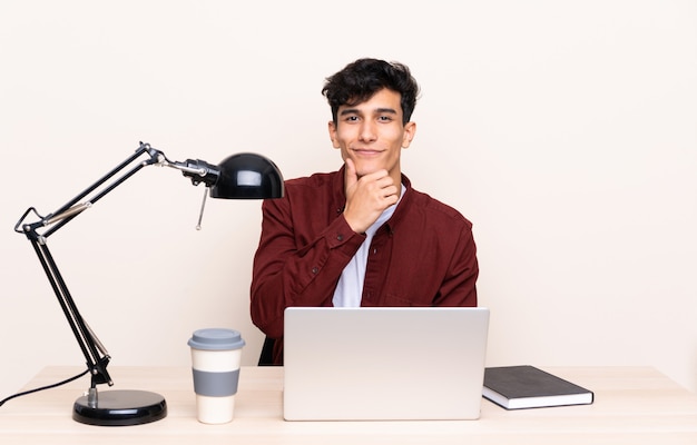 Jonge Argentijnse man in een tafel met een laptop op zijn werkplek lachen