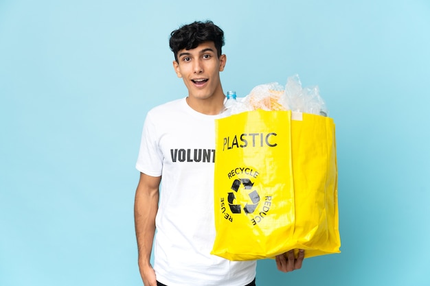 Jonge Argentijnse man met een zak vol plastic met verbazing en geschokte gezichtsuitdrukking