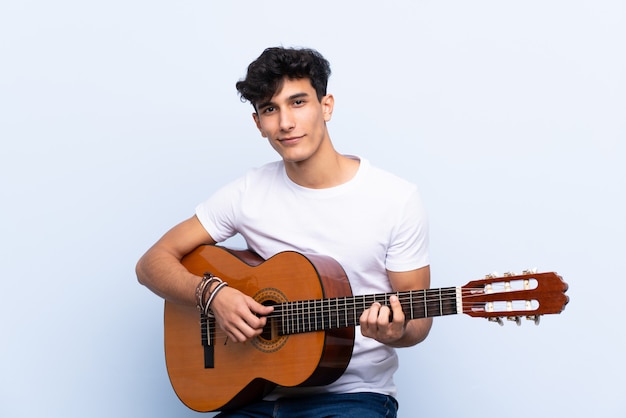 Jonge Argentijnse man met gitaar die en overwinningsteken glimlacht toont