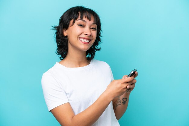 Jonge Argentijnse vrouw geïsoleerd op blauwe achtergrond die een bericht of e-mail verzendt met de mobiel