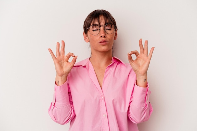 Jonge Argentijnse vrouw geïsoleerd op een witte achtergrond ontspant na een zware werkdag, ze voert yoga uit.