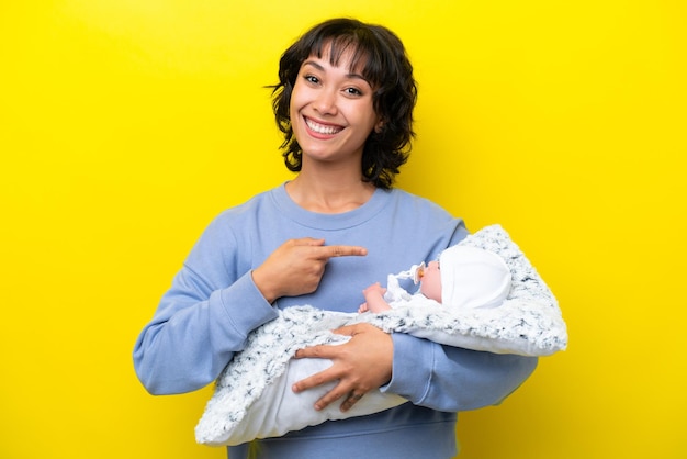 Jonge Argentijnse vrouw met haar schattige baby die naar de zijkant wijst om een product te presenteren