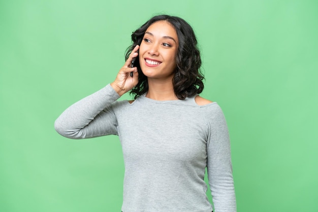 Jonge Argentijnse vrouw over geïsoleerde achtergrond die een gesprek voert met de mobiele telefoon