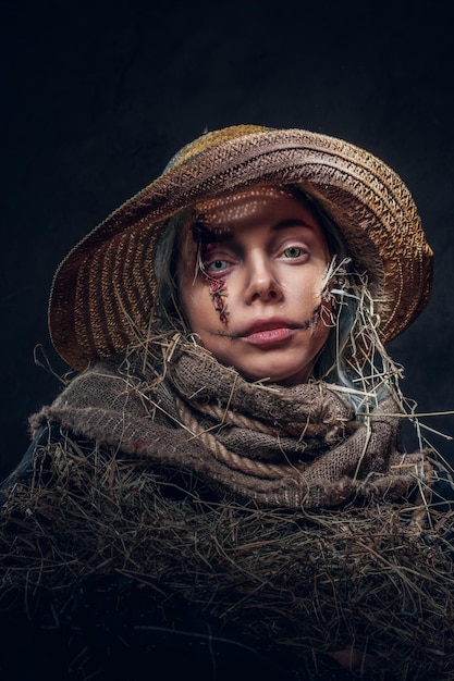 Jonge artistieke vrouw poseert voor fotograaf in een rol van griezelige vogelverschrikker.