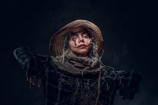 Jonge artistieke vrouw poseert voor fotograaf in een rol van griezelige vogelverschrikker.