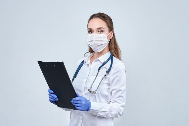 Jonge arts in een medisch masker en handschoenen die omslag houden.