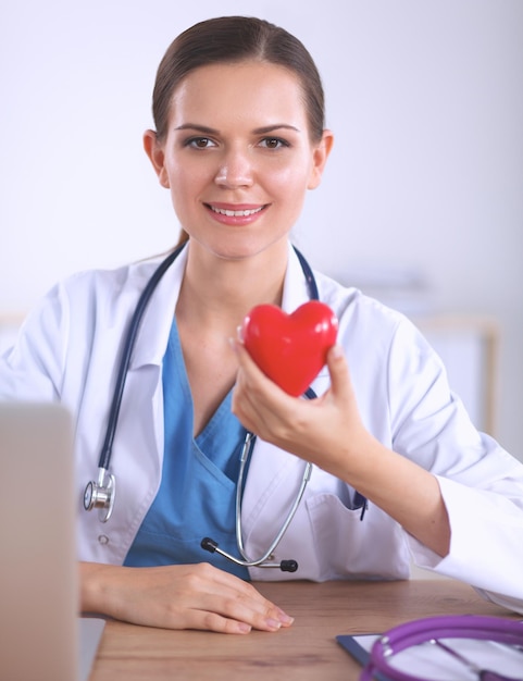 Jonge arts met rood hartsymboolzitting bij bureau