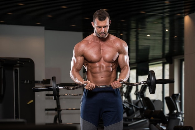 Jonge atleet in de sportschool die bicepskrullen uitvoert met een halter