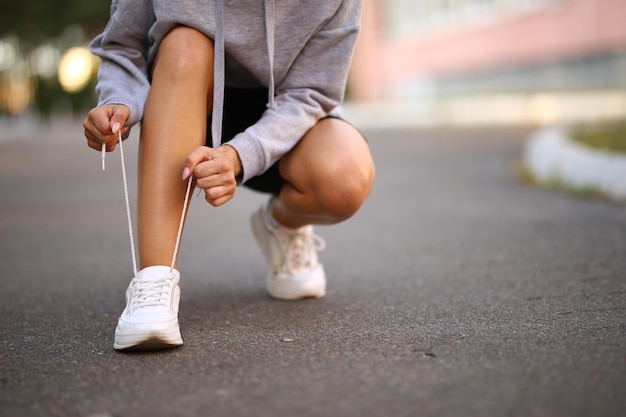 jonge atleet. mooi meisje atleet vergadering koppelverkoop schoenveters op witte sneakers.