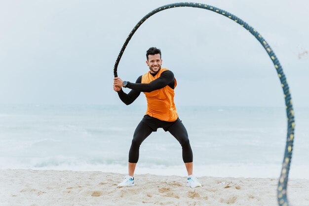 Jonge atleet traint 's ochtends op het strand met touwen