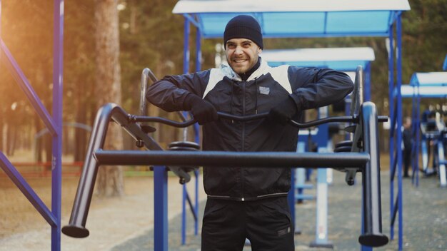 Jonge atletenmens die oefening doet bij openluchtgymnastiek in winterpark