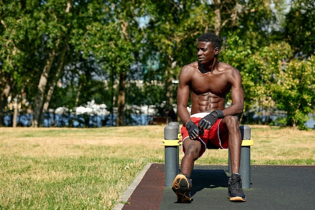Jonge atletische halfnaakte man doet push-ups in het park op de speelplaats. Fitness en buiten oefening Selectieve aandacht, close-up.