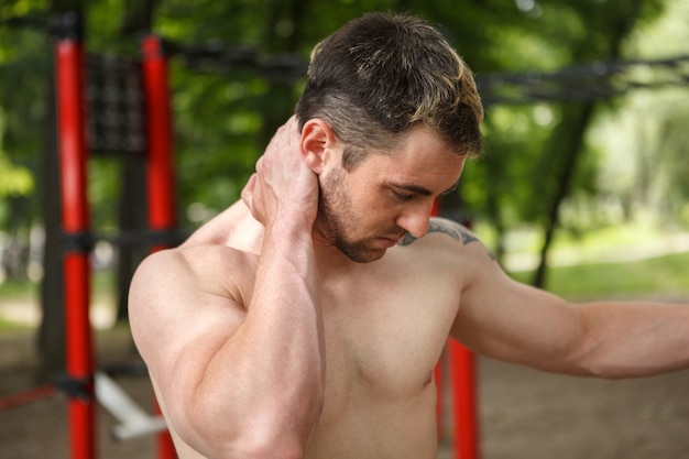 Jonge atletische man die lijdt aan nekpijn, pijnlijke plek masseert