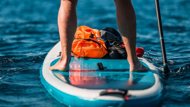 Jonge atletische man roeit op een SUP stand-up paddle board in blauw water zee in Montenegro
