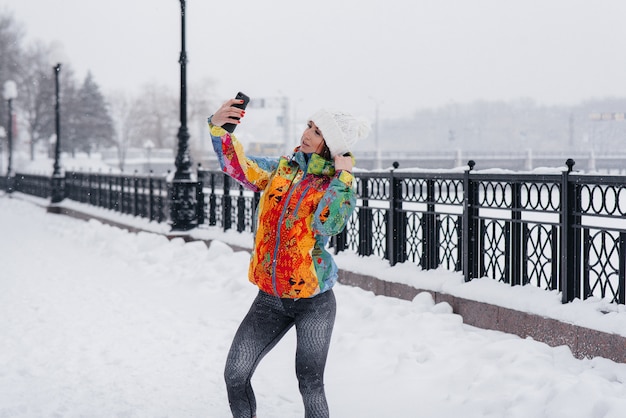 Jonge atletische meisje neemt een selfie op een ijzige en besneeuwde dag. fitness, recreatie