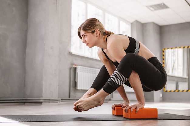 Jonge atletische vrouw balancerend op haar handen, yoga beoefenend